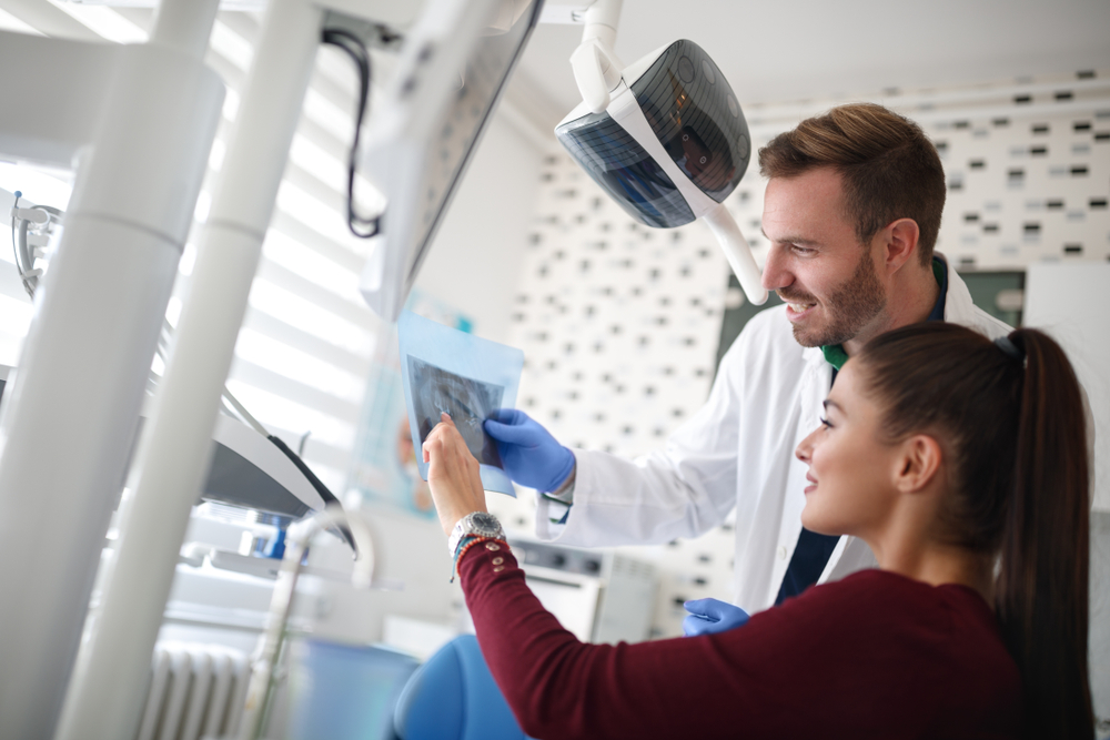 Dentist Showing X-Ray to Patient – Orthodontist San Gabriel A dental professional reviews an X-ray with a smiling patient, explaining treatment details and ensuring clear communication and comfort – Orthodontist in San Gabriel