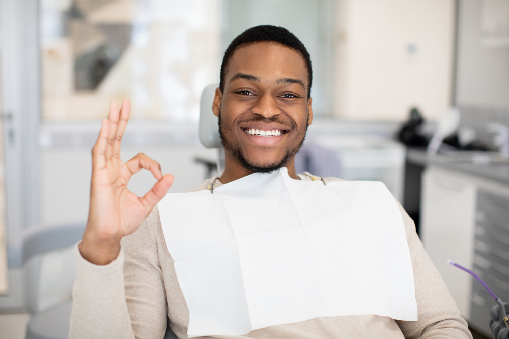 Smiling Patient Giving OK Sign – Orthodontist San Gabriel A cheerful patient sits comfortably in the dental chair, giving an OK hand gesture to show trust and positivity during his orthodontic visit – Orthodontist San Gabriel