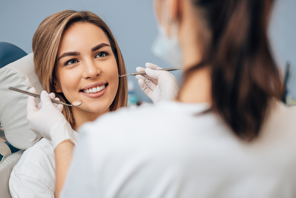 Woman Receiving Dental Exam – Orthodontist Pasadena A patient smiles confidently while a dental professional performs a gentle checkup, showcasing comfort and excellent oral health – Orthodontist Pasadena.