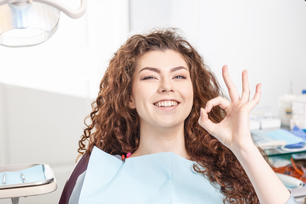 Happy Patient Giving OK Sign – Orthodontist in South Pasadena A cheerful young woman sits in the dental chair and gives an OK hand gesture, showing confidence and satisfaction with her orthodontic care – Orthodontist in South Pasadena.